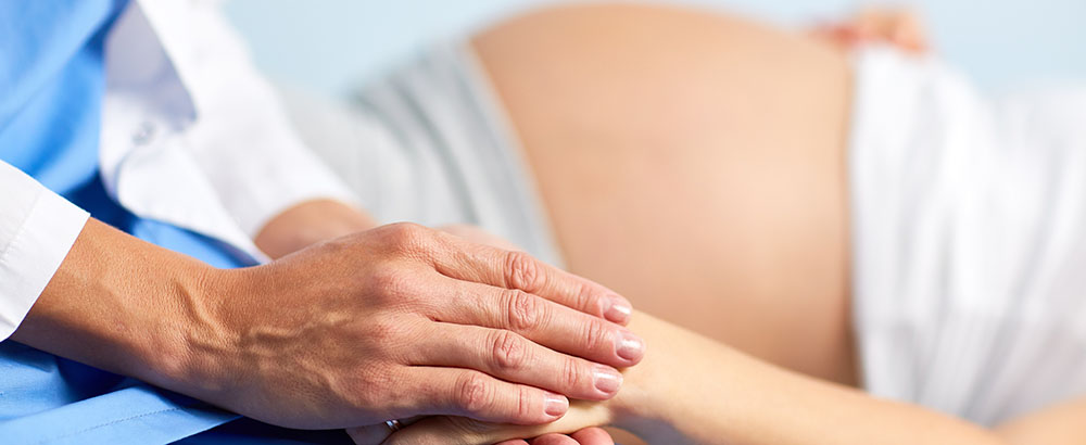 Pfleger hält Hand einer Schwangeren