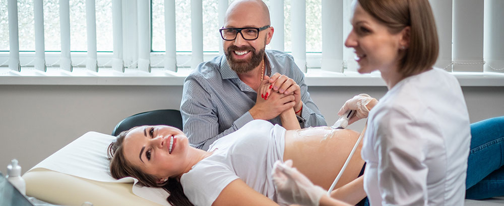 Schwangere Frau mit Mann beim Ultraschall
