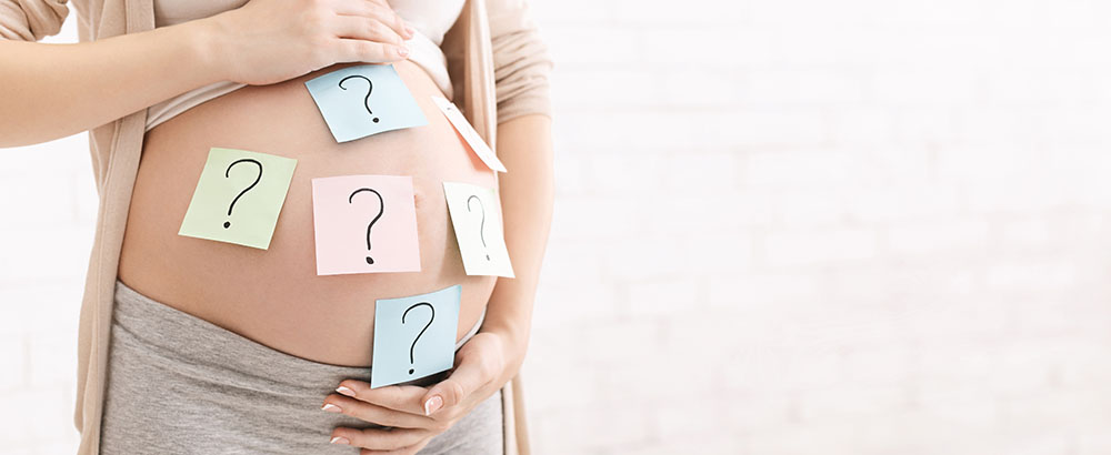 Bauch einer Schwangeren auf dem Post-Its mit Fragezeichen sind