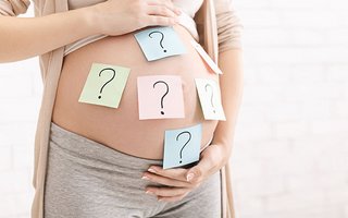 Bauch einer Schwangeren auf dem Post-Its mit Fragezeichen sind